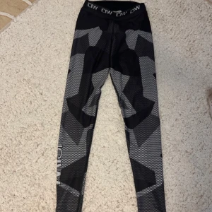 Svarta och grå leggings från ICW - Snygga svarta och grå leggings från ICW med ett coolt geometriskt mönster. Perfekta för träning med en bekväm passform och elastisk midja. Märkeslogga synlig på midjebandet.