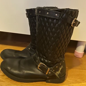 Svarta quiltade stövlar från Replay - Snygga svarta stövlar från Replay med quiltad design och dekorativa spännen. Perfekta för en stilren look med en touch av edge.