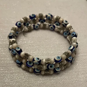 Flerfärgat armband med ögonmotiv - Unikt armband med flera rader av pärlor i blått, vitt och silver. Pärlorna har ett ögonmotiv och är dekorerade med små silverfärgade detaljer. Perfekt för att ge en bohemisk touch till din stil.