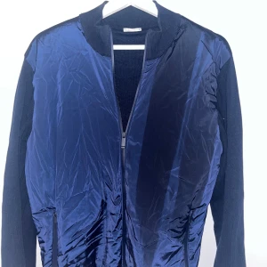 Blå cardigan från John Henric - Snygg blå cardigan från John Henric med dragkedja framtill. Jackan har en stilren design med ribbad krage och ärmslut. Perfekt för en casual look. Storlek M