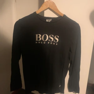 Svart långarmad tröja från Hugo Boss - Snygg svart långärmad tröja från Hugo boss. Perfekt för en stilren och avslappnad look. Det är toppskick på tröjan och den är i storlek S, tveka inte att höras av vid intresse 😊