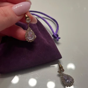 Droppformade örhängen  - Snygga, eleganta och glittriga örhängen med en droppformad design. De har en stor klar sten i mitten omgiven av mindre stenar. Perfekta till ett extra tillfälle. Aldrig använda 