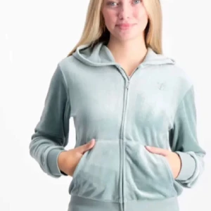Mintgrön hoodie från Juicy Couture - Mysig mintgrön hoodie från Juicy Couture i mjukt material. Den har en dragkedja framtill och en broderad logga på bröstet. Perfekt för en avslappnad stil. Det står storlek 14/15 så jag antar att det är storlek S.