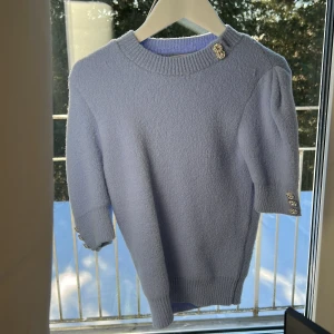 Ljusblå tröja med dekorativa knappar - Säljer en ljusblå/ljuslila tröja med dekorativa knappar på axeln och ärmslut. Tröjan har trekvartsärm och är tillverkad i ett mjukt material som ger en mysig känsla. Perfekt för kyligare dagar. Den är strl S men passar XS tror även att den passar XXS💓