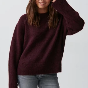 Vinröd stickad tröja - Mysig vinröd stickad tröja med långa ärmar och ribbade detaljer vid ärmslut och nederkant. Aldrig använt och har prislappen kvar.