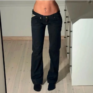 Svarta jeans med nitar från Replay - Snygga svarta jeans från Replay med coola nitar på bakfickan som formar ett 'R'. De har en lågmidjad passform, midjemåttet är 40 cm och innerbenslängden är 74,5cm☺️