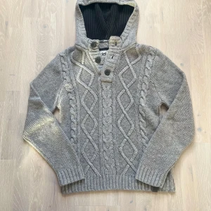Unik cardigan - Säljer en riktigt fet grå stickad hoodie med ett unikt flätmönster på. Riktigt stilig och i mycket bra skick!