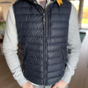 Blå parajumpers väst  - Säljer en snygg mörkblå dunväst från Parajumpers. Västen har en praktisk dragkedja och en gul detalj vid kragen. Perfekt för lager-på-lager under kyliga dagar. Mycket bra skick och såklart äkta. Ny pris 4699kr Nu endast 1100kr🔥🔥🔥Kom gärna med pris förslag!!!  