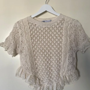 Beige spetsmönstrad topp från Zara - Charmig beige topp från Zara med spetsmönster och volangdetaljer. Aldrig använd.