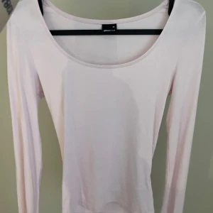 Ljusrosa långärmad topp med slits från Gina Tricot - Säljer en stilren ljusrosa långärmad med slits på ärmarna från Gina Tricot. Perfekt för en enkel och snygg look. Toppen har en rund halsringning och är gjord i ett mjukt material.