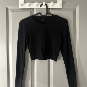 Svart ribbad croppad tröja  - Snygg svart ribbad tröja från Monki med långärmad design. Tröjan är croppad och har en stilren look som passar perfekt till olika outfits❣️