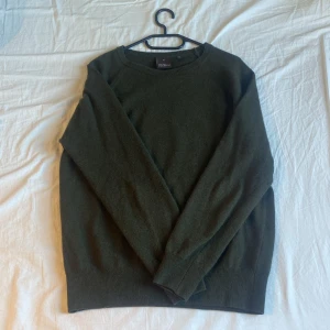 Grön tröja från Oscar Jacobson - Säljer en stilren grön tröja från Oscar Jacobson, tillverkad i Italien. Tröjan har en klassisk design med rund hals och långa ärmar, perfekt för en elegant och avslappnad look.