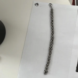 Silverfärgat armband med kedjedesign - Snyggt silverfärgat armband med en unik kedjedesign. Perfekt för att ge en stilren touch till din outfit. Armbandet har en säker låsning och passar de flesta handleder.