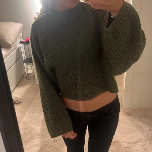 Grön stickad tröja från Gina Tricot - Säljer en snygg grön stickad tröja från Gina Tricot. Tröjan är croppad med långa ärmar och har en mysig, ribbad design. Perfekt för kyligare dagar! 💚