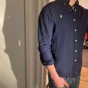 Ralph Lauren Skjorta - Tja säljer en Ralph lauren skjorta 100% linne i färgen marinblå och i storlek S passar 170-180 cm ungefär. Nypris 1595 KR mitt pris 299 KR. Inga defekter som hål eller fläckar. Skriv vid frågor eller funderingar.