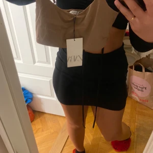 Beige linnetopp från Zara - Säljer en beige linnetopp från Zara. Toppen har justerbara axelband och en enkel design som passar perfekt till sommaren. Den är tillverkad i ett mjukt och bekvämt material.