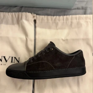 Svarta sneakers från Lanvin - Snygga svarta sneakers från Lanvin i mocka med skinn detaljer. Skorna har en klassisk design med snörning och en låg profil. Perfekta för en stilren look.