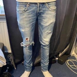 Dondup George - Snygga blå skinny jeans från Dondup med slitna detaljer och en cool, distressed look. Perfekta för en avslappnad stil. De har en klassisk femficksdesign och knappgylf. Modell: Dondup | Priset ej hugget i sten ❌| Hål i skrevet ⚠️|