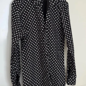  Style of Norrland  - Snygg svart skjorta med vitt mönster från Style of Norland. Skjortan har långa ärmar och knappar framtill. Perfekt för en stilren look.