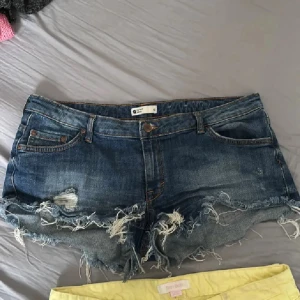 Blå jeansshorts med slitna detaljer - ‼️OBS inga bilder med dem på ‼️Snygga blå jeansshorts från H&M med slitna detaljer och fransar vid benen. Perfekta för en avslappnad stil. De har en klassisk femficksdesign och knappgylf. 43 cm midjemått rakt över❤️