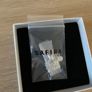 Silverhalsband från Safira - Elegant silverhalsband från Safira, levereras i en stilren vit förpackning. Perfekt för att ge en touch av klass till din outfit. Halsbandet har en fin kedja och ett hänge format som en droppe. 