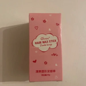 Hårvaxstick från O'Cheal - Praktisk hårvaxstick från O'Cheal för att enkelt styla och tämja håret. Innehåller ingredienser som petrolatum, bivax och mineralolja. Perfekt för att hålla håret på plats och ge en snygg finish. Kommer i en söt rosa förpackning med hjärtmönster.