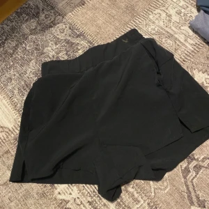 Svarta shorts med resårmidja - Snygga svarta shorts med elastisk resårmidja för en bekväm passform. Perfekta för en avslappnad stil. De har en enkel design utan extra detaljer, vilket gör dem lätta att matcha med olika outfits.