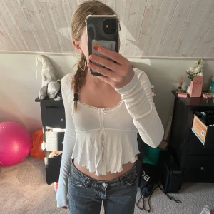 Vit långärmad topp från Gina Tricot - Säljer en söt vit långärmad topp från Gina Tricot. Toppen är croppad med volangdetaljer och har en knytning framtill. Jättefin till ett par jeans! Andvänd fåtal gånger och i väldigt fint skick. Pris kan diskuteras!💕