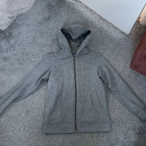 Grå hoodie från Jack & Jones - Säljer en stilren grå hoodie från Jack & Jones. Den har en dragkedja framtill och en bekväm huva. Perfekt för en avslappnad look.