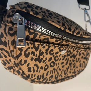 Leopardmönstrad magväska  - Snygg leopardmönstrad magväska från New Look med dragkedja och justerbar rem. Perfekt för att ge din outfit en trendig touch. Väskan har en praktisk storlek för att bära dina nödvändigheter. SKRIV VID FRÅGOR!!🥰