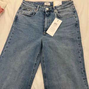  Only juicy Jeans - Snygga blå jeansbyxor från Only med en avslappnad wide fit. Byxorna har en klassisk femficksdesign och är högmidjade för en modern look. Perfekta för en stilren vardagsoutfit. 