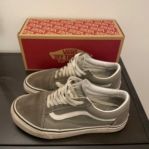 Gråa Vans sneakers - Säljer ett par gråa Vans sneakers med klassisk vit sidosymbol och snörning. Skorna har en vit sula och är tillverkade i mocka. Perfekta för en avslappnad stil. Skriv om du har funderingar och priset är inte hugget i sten!