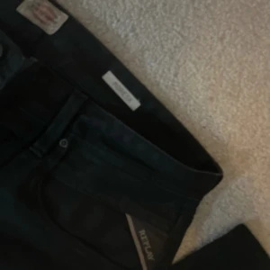replay jeans - Svart replay jeans i modellen moresk. Storlek 32 lite grön färg vid knapparna se bild 3 men de är inte lika tydligt i vanligt ljus. Priset är diskuterbart 