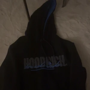 Svart hoodie från Hoodrich - Säljer en svart hoodie från Hoodrich med blå detaljer och text på framsidan, baksidan och små detaljer, säljer för jag inte använder den