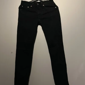Svarta jeansbyxor ifrån Lewis, 511 - Snygga svarta jeansbyxor med en klassisk design. De har en rak passform och är perfekta för en stilren look. Byxorna har knappar och dragkedja framtill samt fickor både fram och bak. Jeansen är i storlek 27/32 men skulle säga att dom är i typ 27/30 jag är 170 och sitter bra på mig. 