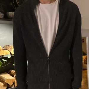 Mörkgrå Kashmir zip up - Säljer en stilren mörkgrå kashmir zip up. Perfekt för kyliga dagar samt varma, enkel att matcha med olika outfits. Koftan har långa ärmar och en bekväm passform. Pris går att diskutera vid snabb affär såklart.
