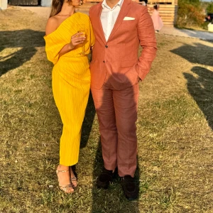 Gul festklänning  -  Klänningen har en off-shoulder design och är plisserad för en elegant touch. Perfekt för sommarens festligheter.