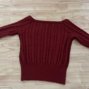 Röd stickad tröja - Säljer en snygg röd stickad tröja med kabelstickat mönster. Tröjan har långa ärmar och en bred ribbad kant vid nederdelen. Perfekt för kyligare dagar.