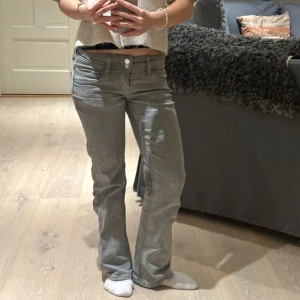 Grå bootcut jeans - Snygga grå bootcut jeans med låg midja och klassisk femficksdesign. Jeansen har en dragkedja och knapp framtill. Perfekta för en avslappnad stil. De är lite slitna nertill byxorna men inget som riktigt syns så mycket när man har på sig de!
