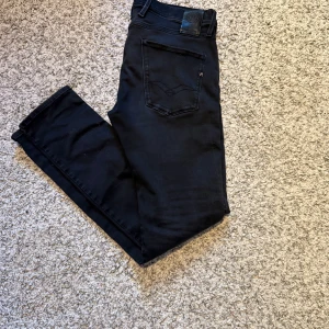 Svarta jeans från Replay modell anbass - Modell Anbass ! Snygga svarta jeans från Replay med en klassisk femficksdesign. De är tillverkade i ett bekvämt material som ger en bra passform. Perfekta för en stilren look. Mycket bra skick!