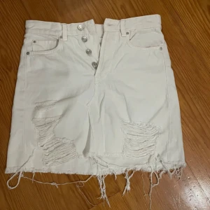 Vit jeanskjol med slitningar - Snygg vit jeanskjol med slitna detaljer från H&M. Storlek 36! 