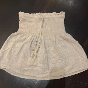 Beige kjol från Zara - SUPER FIN beige kjol från Zara!❤️Jätte söta snäckor och andra detaljer på snörena. Säljer för den inte passar på mig längre❤️