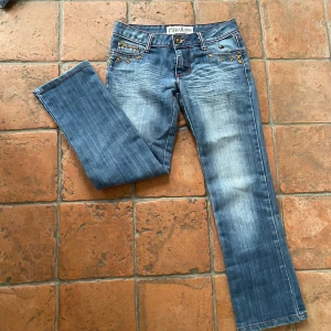 Blå jeans med broderade detaljer - Snygga blå jeans  med unika broderade detaljer i gult på fickorna. Jeansen har en flare passform och är perfekta för en avslappnad stil. Aldrig andvänt och köpt på Vinted. Kan inte skicka bild på då de inte passar! Midjemått:37 Innerbenslängd:69
