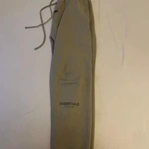 Beige mjukisbyxor från Essentials - Säljer ett par bekväma beige mjukisbyxor från Essentials Fear of God. Byxorna har en elastisk midja med dragsko och en bakficka. Perfekta för en avslappnad stil.