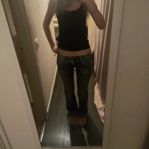 Blå jeans från Hilfiger - Snygga blå jeans från Hilfiger med slitna detaljer och bootcut-stil. De har en låg midja och klassiska femficksdesign. Perfekta för en avslappnad look. Dem är lite slitna i rumpan men det syns inte på, mått på sista sidan!!