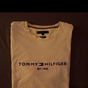 Gul t-shirt från Tommy Hilfiger - Säljer en gul t-shirt från Tommy Hilfiger med tryck 'Est. 1985' på bröstet. T-shirten har en slim fit passform och korta ärmar. Perfekt för en stilren och avslappnad look. Är (xl) men slim fit så passar även ( m )