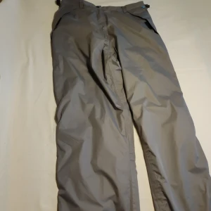 Grå täckbyxor från 2117 of Sweden - Säljer ett par grå täckbyxor från 2117 of Sweden. Byxorna har elastisk midja och är tillverkade i ett slitstarkt material med Tritech-teknologi för extra skydd mot väder och vind. Perfekta för utomhusaktiviteter under kalla dagar.