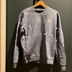 Blå sweatshirt från Scotch & Soda - Säljer en stilren blå sweatshirt från Scotch & Soda. Tröjan har en rund halsringning och en liten logotyp på bröstet. Perfekt för en avslappnad stil. Tillverkad i Turkiet.Det är en vuxen storlek på denna👍