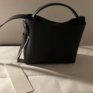 Svart axelväska från Arket - Snygg svart axelväska från Arket i stilren design. Helt ny, aldrig använt. Nypris: 1390kr. 