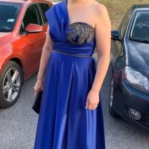 Festklänning  - Säljer min eleganta blå satinklänning med pärlor i storlek 42. Ordinarie pris 4500kr, säljer för 1900kr. Använd bara en gång och vid intresse kan fler bilder skickas. Perfekt för en speciell kväll som till balen eller ett bröllop!